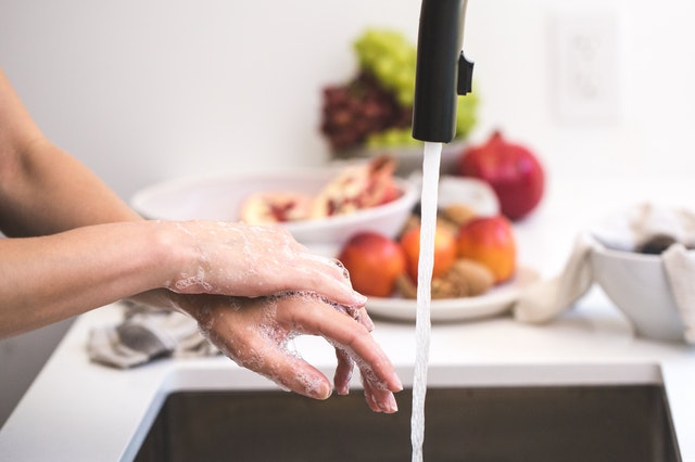 Mujer lavándose las manos en la cocina